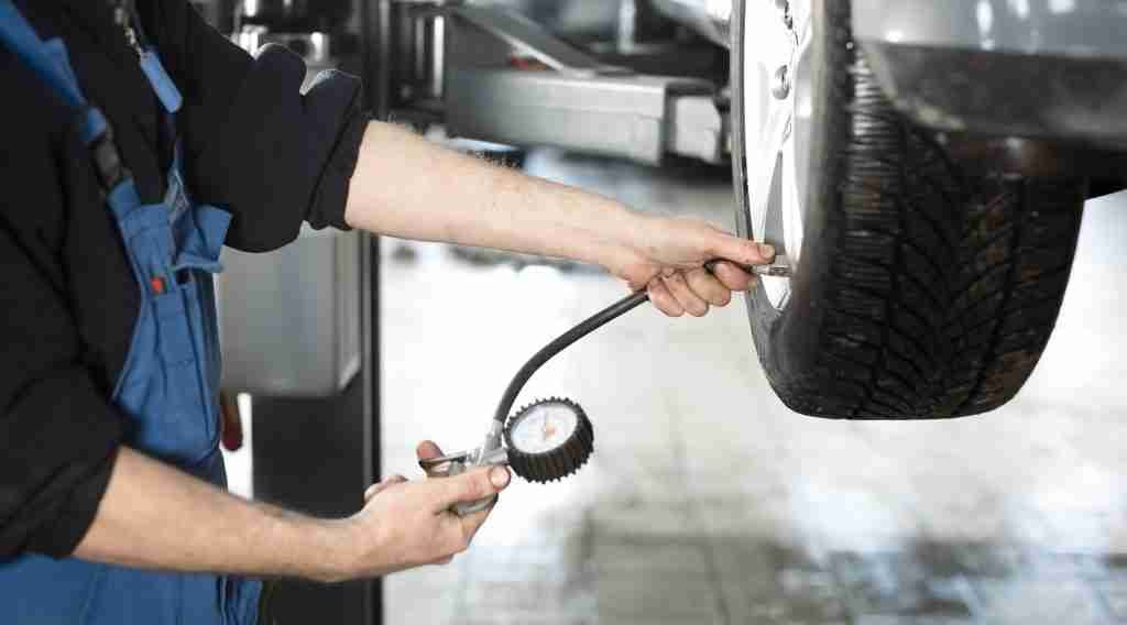 Mechanic checking tyre pressure at the wheel